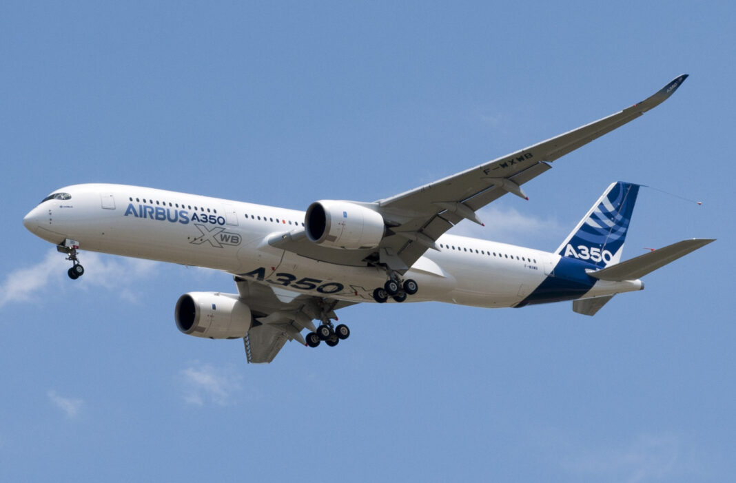 Airbus A350 pri nízkom prelete nad závodom Airbusu v Toulouse, pohľad zospodu na krídlo a motory