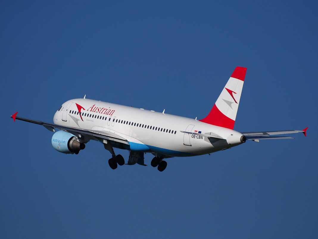 Airbus A320 spoločnosti Austrian Airlines krátko po vzlete, pohľad zboku zdola na stúpajúce lietadlo s vysunutým podvozkom