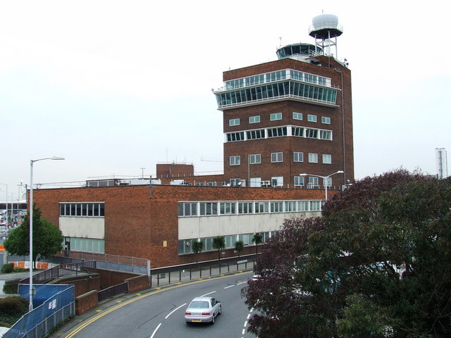 Výpadok riadenia letov ochromil Londýn. Náhrada nepatrí. Riadiaca veža Letiska Londýn-Heathrow v pohľade zdola, v pozadí terminálové budovy