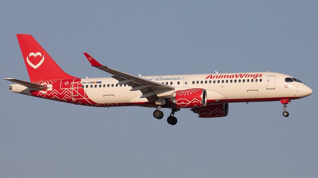 Airbus A220-300 rumunskej aerolinky AnimaWings v červeno-bielych farbách s vysunutým podvozkom krátko pred pristátím.
