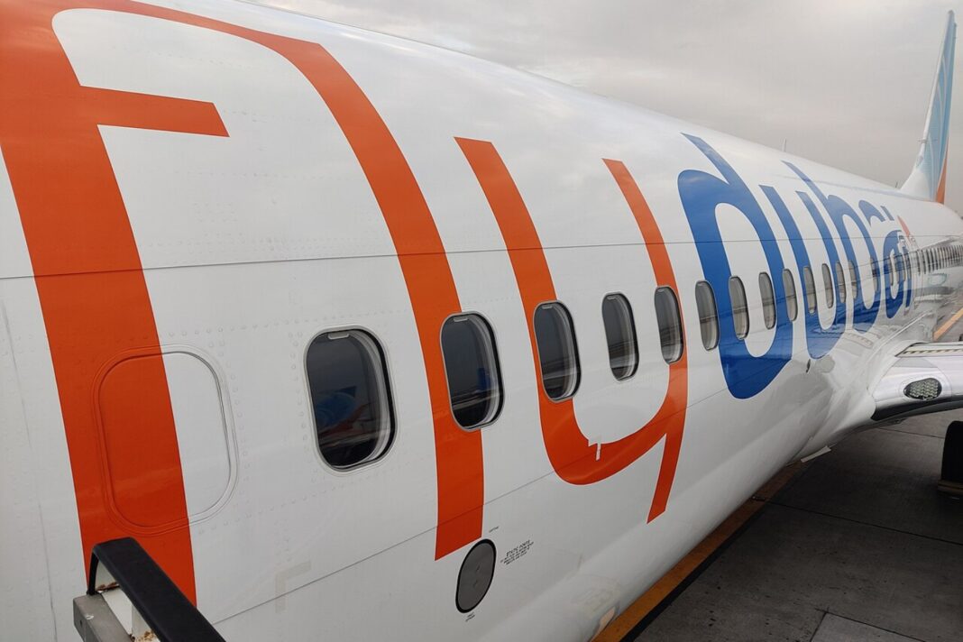 Detail trupu Boeingu 737 spoločnosti flydubai s oranžovo-modrým nápisom, pri dverách sú pristavené nástupné schody.