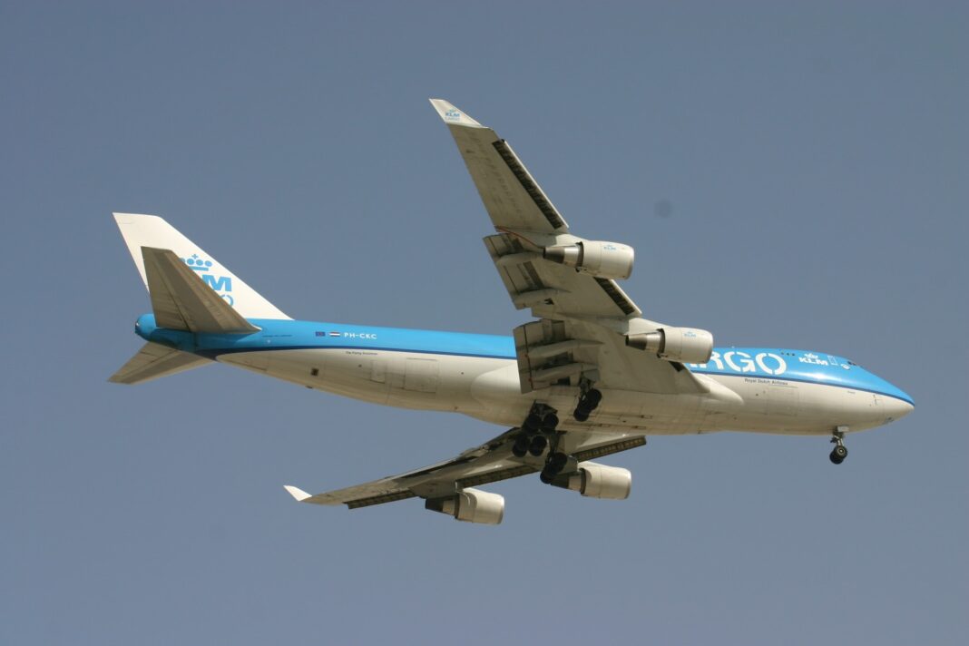 Nákladný Boeing 747-400ERF v modro-bielych farbách KLM Cargo stúpa po štarte, pohľad zdola zboku proti jasnej oblohe.