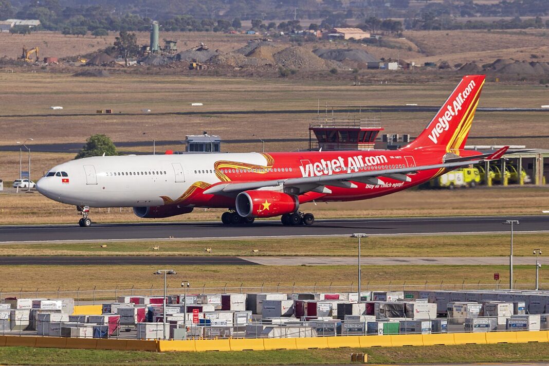 Červeno-žltý Airbus A330-300 spoločnosti VietJet Air na letiskovej dráhe za denného svetla, bočný záber